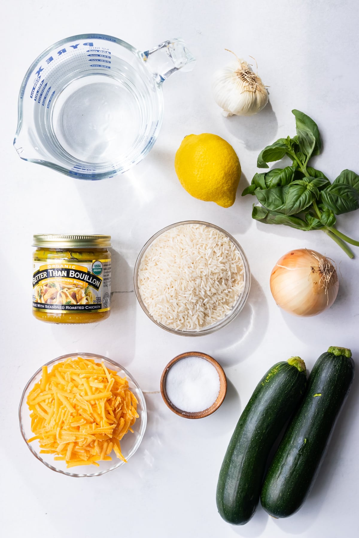 Ingredients for zucchini rice including zucchini, cheddar cheese, basil, lemon, and rice
