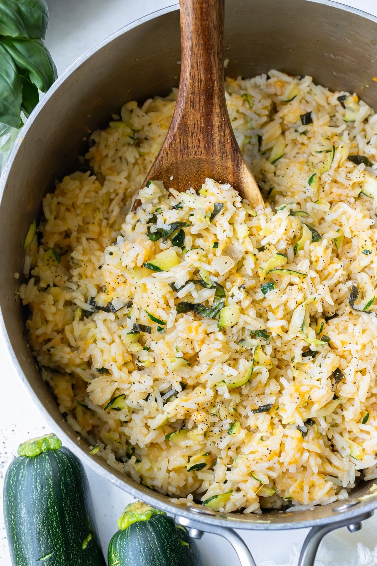 A pot of creamy zucchini rice with a wooden spoon