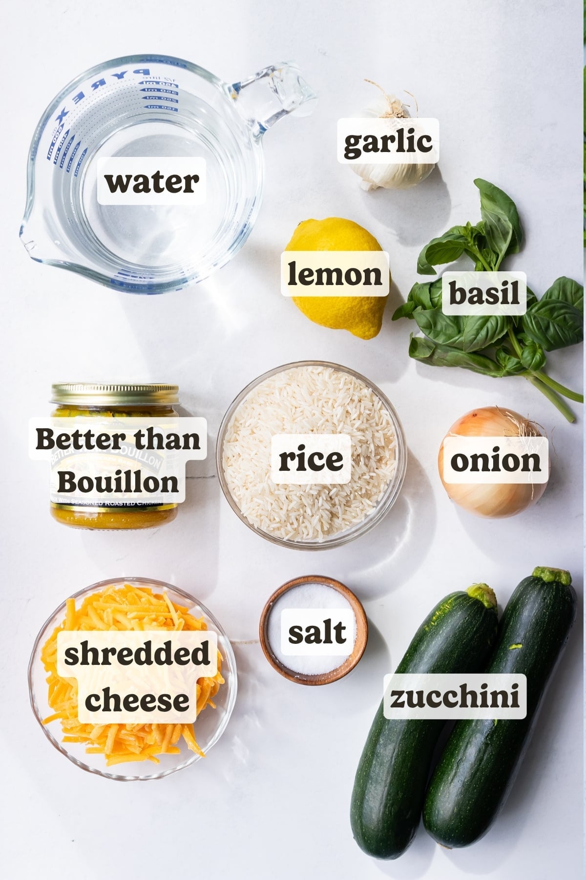Ingredients for zucchini rice including zucchini, cheddar cheese, basil, lemon, onion, and basmati rice