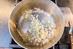 Diced onion cooking in a pot to start cheesy zucchini rice