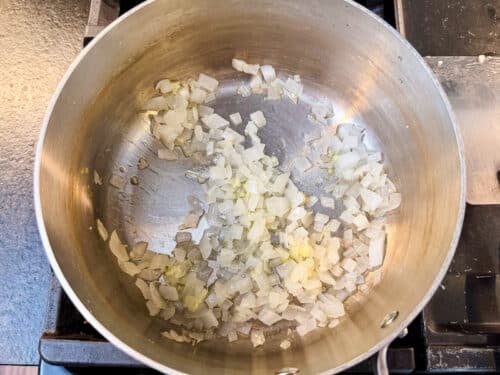 Diced onion cooking in a pot to start cheesy zucchini rice