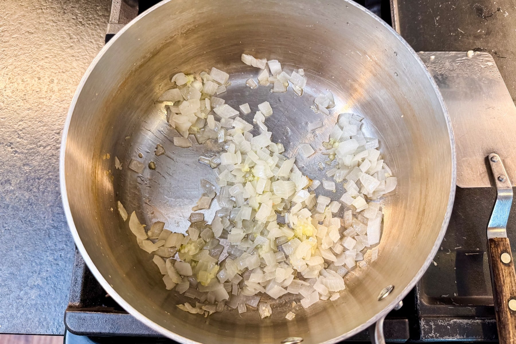 Diced onion cooking in a pot to start the cheesy zucchini rice