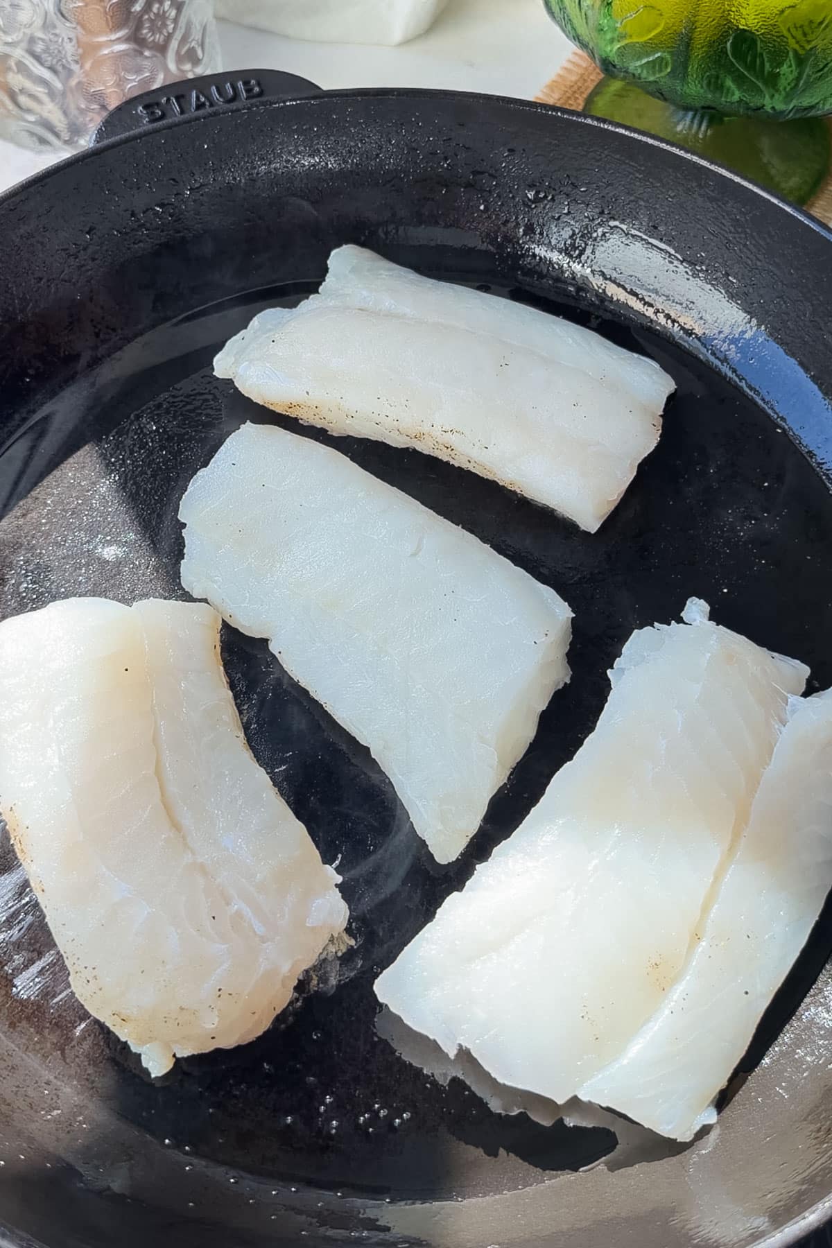 Cod fillets developing a golden crust in the skillet.
