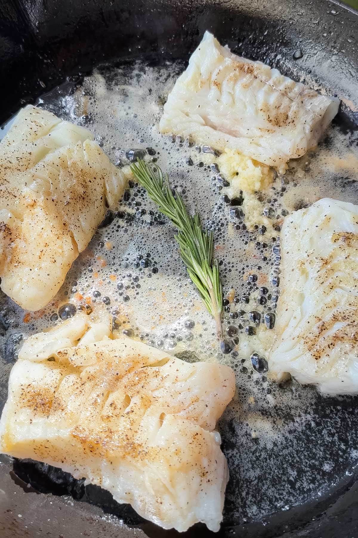 Butter and rosemary melting around cod for garlic butter cod.