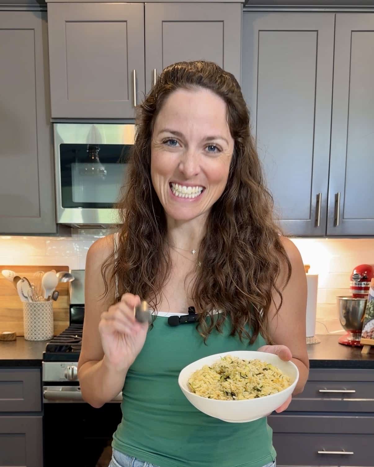 London Lea holding a bowl of cheesy zucchini rice in her Austin, TX kitchen.