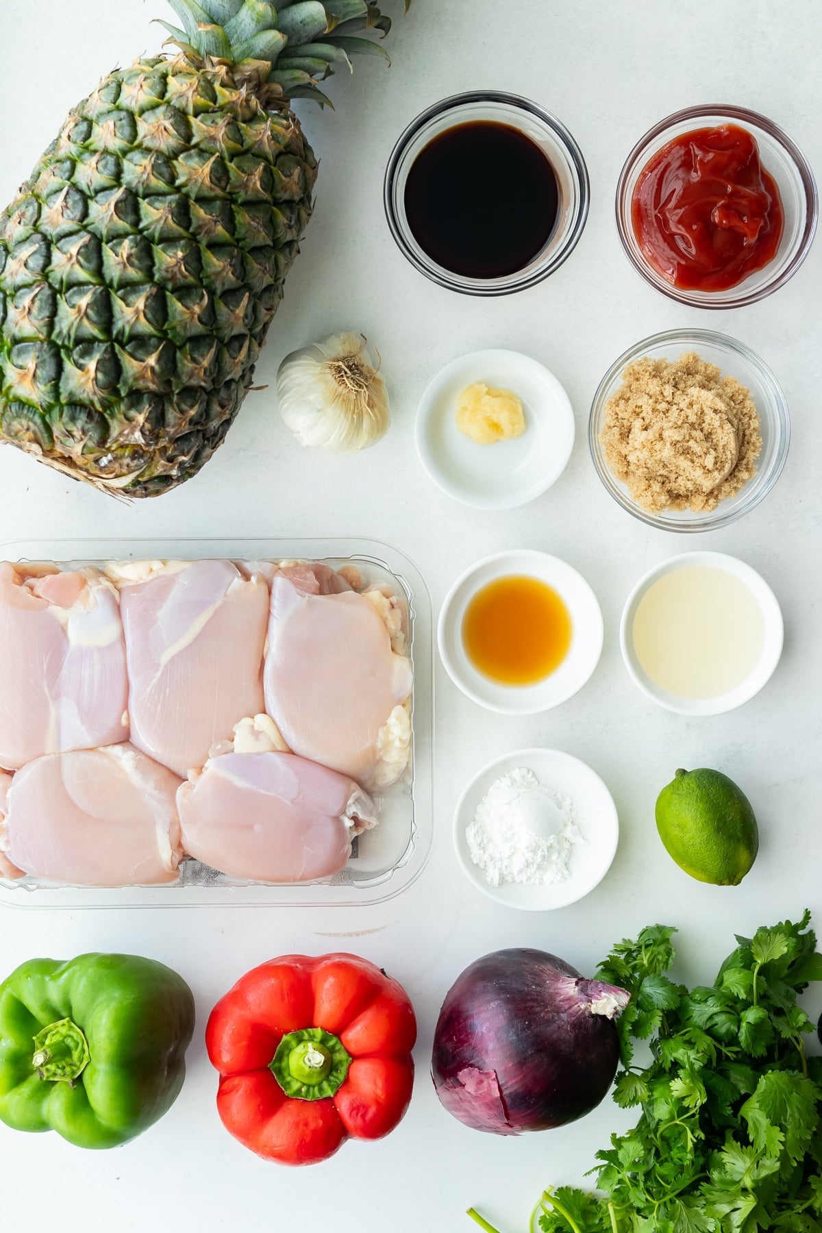 Chicken thighs, a pineapple, marinade ingredients, bell peppers, and a red onion are the ingredients needed for a sheet pan hawaiian chicken recipe.