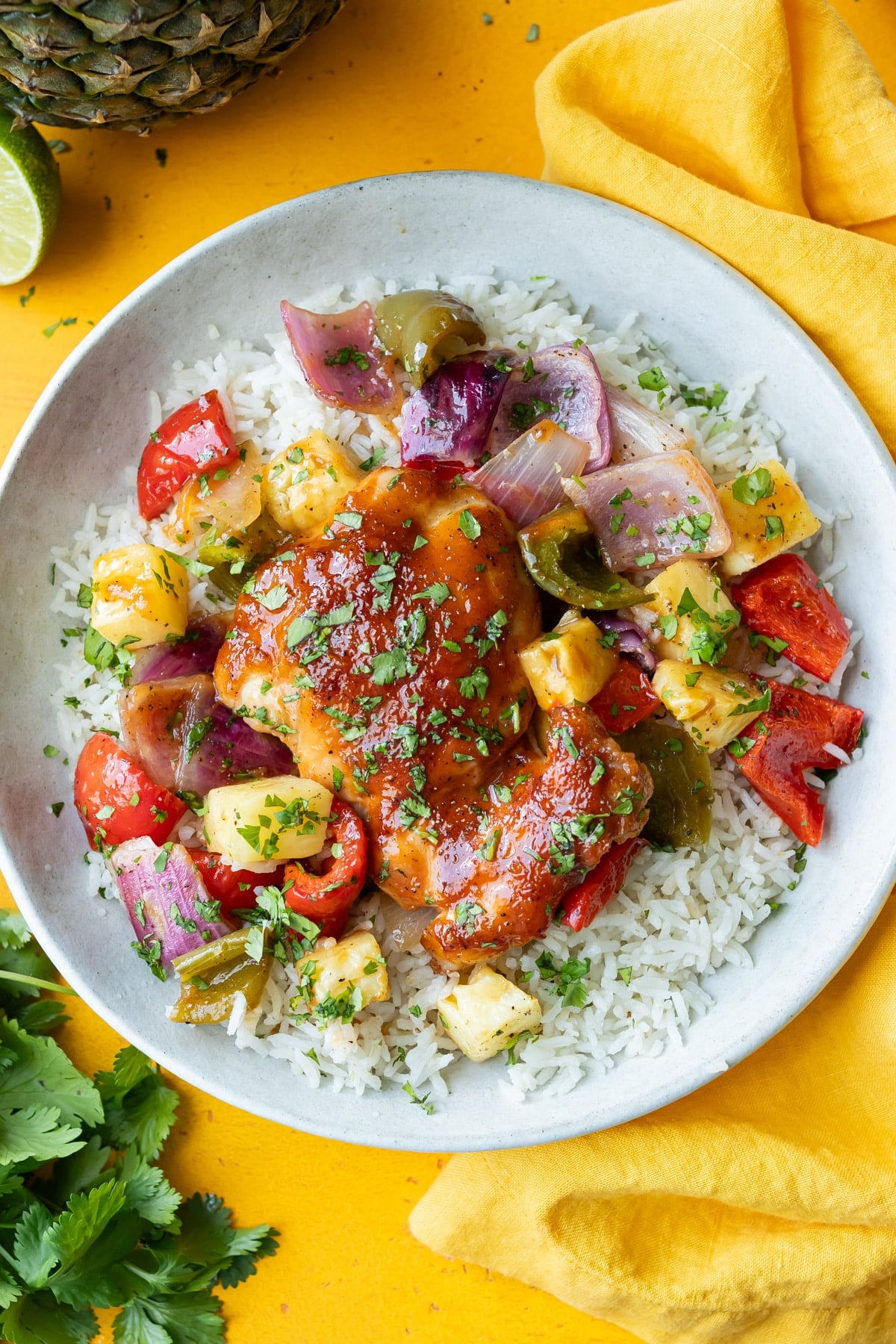 A hawaiian chicken rice bowl with chicken thighs, pineapple, and bell peppers is served.