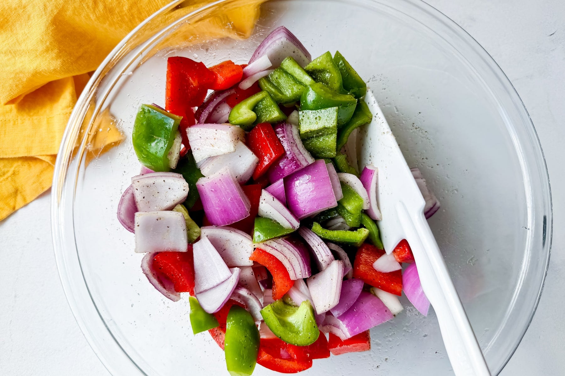 Chopped red and green bell peppers with red onion in a bowl for easy sheet pan Hawaiian chicken.