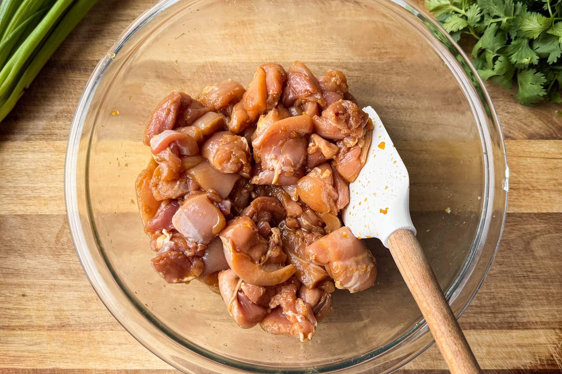 Cut chicken thighs tossed in the soy and lime marinade in a glass bowl.