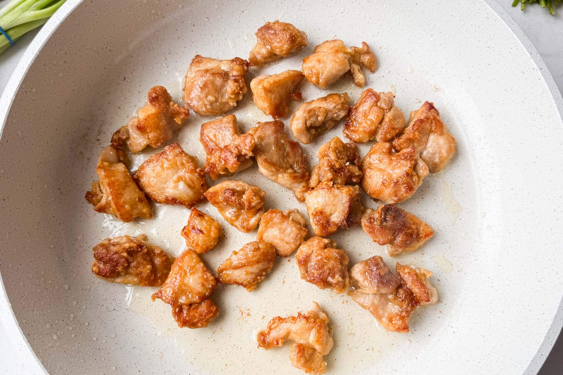 Golden brown crispy chicken bites finished cooking in a white skillet for bang bang chicken bowls.