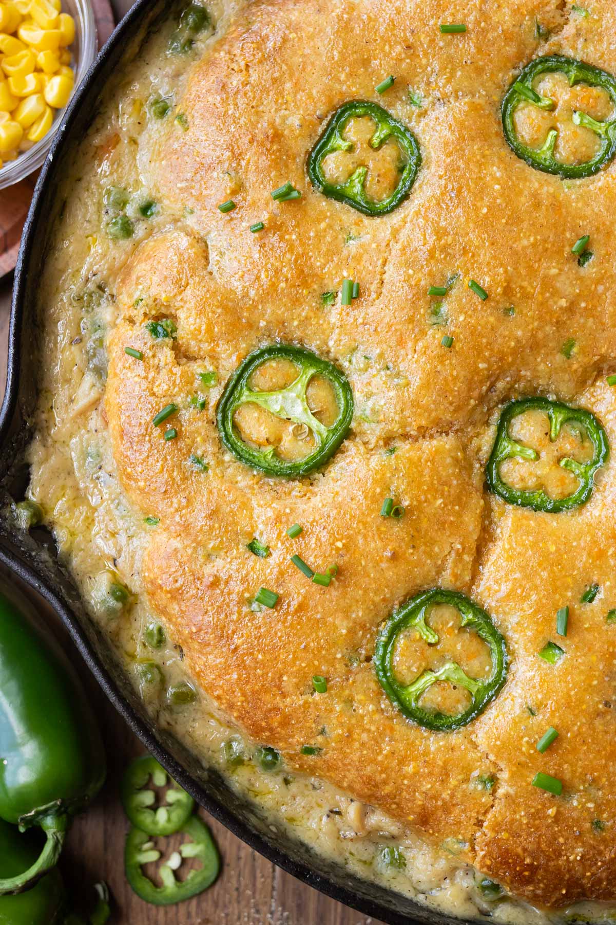 A jalapeno cornbread is on top of a chicken pot pie in a cast iron skillet.