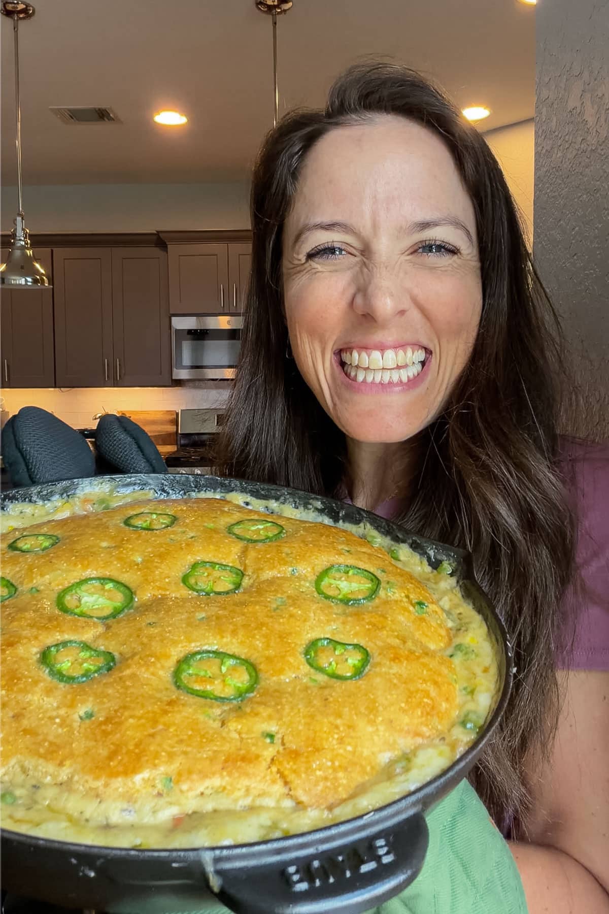 London Lea holding a cornbread chicken pot pie with her honey jalapeno cornbread topping in her Austin, Texas kitchen.