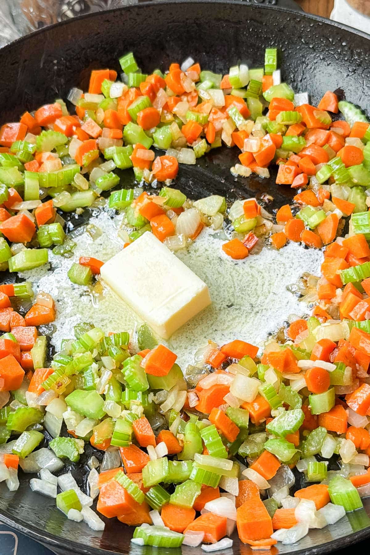 Mirepoix of onions, celery and carrots are cooked in a cast iron skillet.