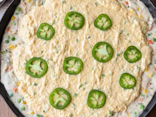 The jalapeno cornbread topping is spread on top of the chicken pot pie filling in one pan.