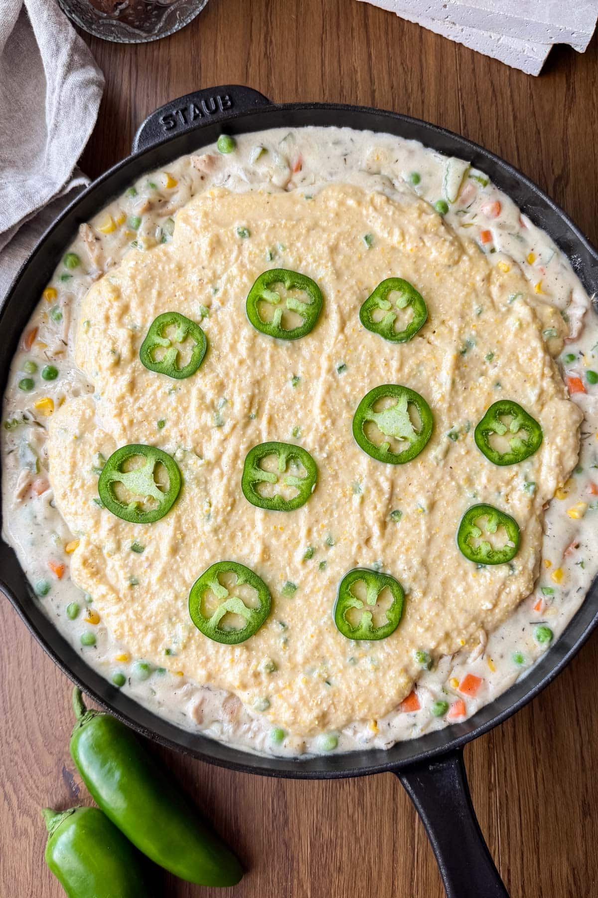 The jalapeno cornbread topping is spread on top of the chicken pot pie filling in one pan.