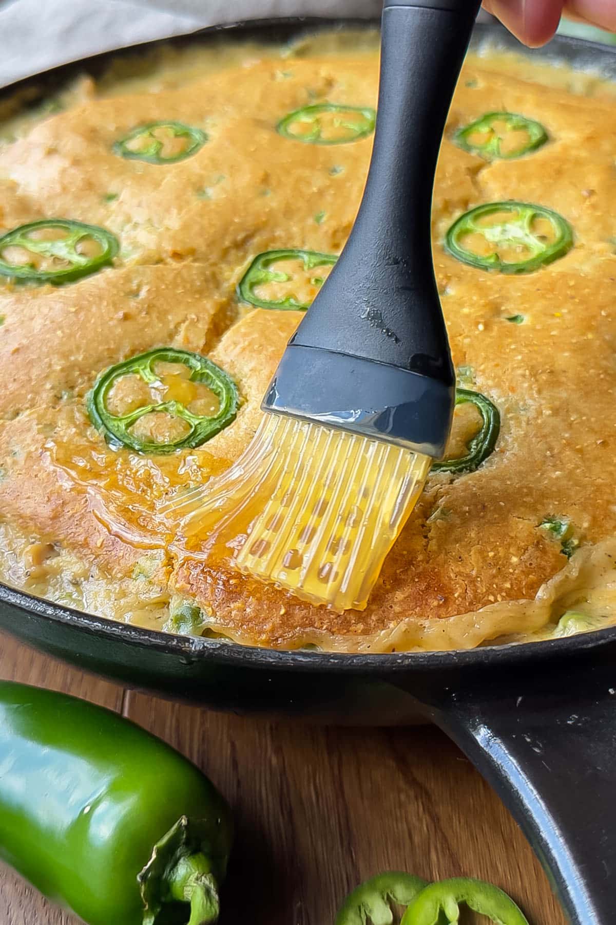 Honey butter is brushed over the top of the cornbread chicken pot pie recipe after baking.