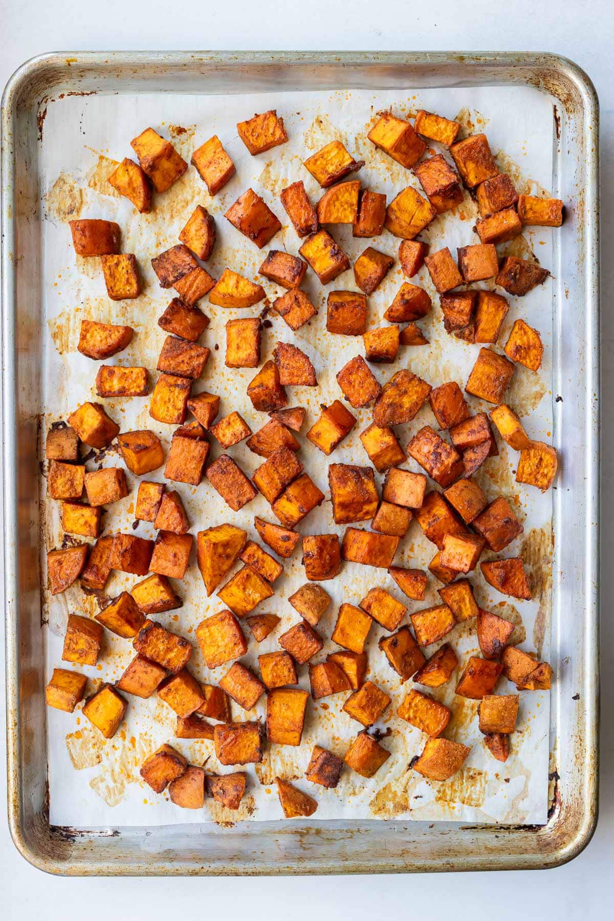 Crispy roasted sweet potato cubes on a sheet pan after baking at 400 degrees.