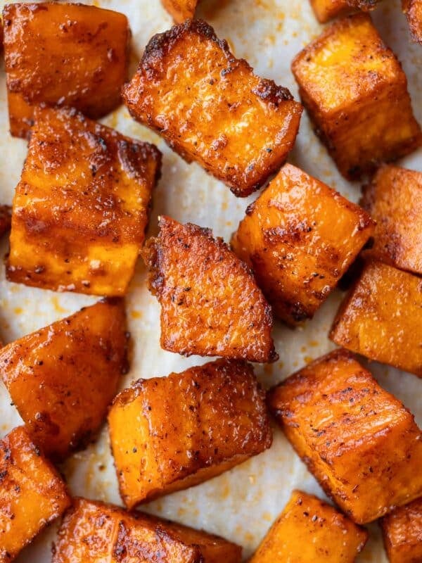 Crispy roasted sweet potato cubes are on a baking sheet.