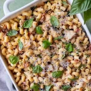 Marry Me Chicken Pasta dump-and-bake recipe is served with fresh basil and Parmesan cheese in a baking dish.