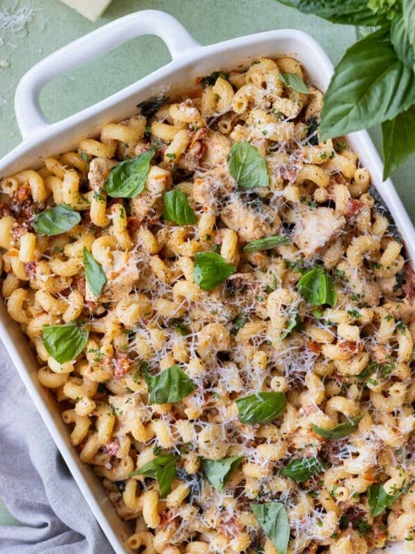 Marry Me Chicken Pasta dump-and-bake recipe is served with fresh basil and Parmesan cheese in a baking dish.