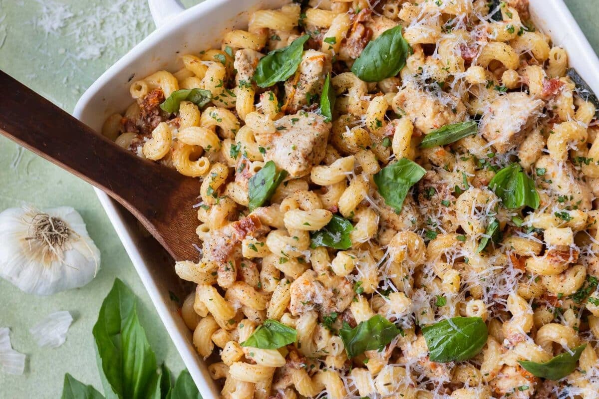 A spoon scoops up a serving of a Marry Me Chicken Pasta Bake recipe from a baking dish.