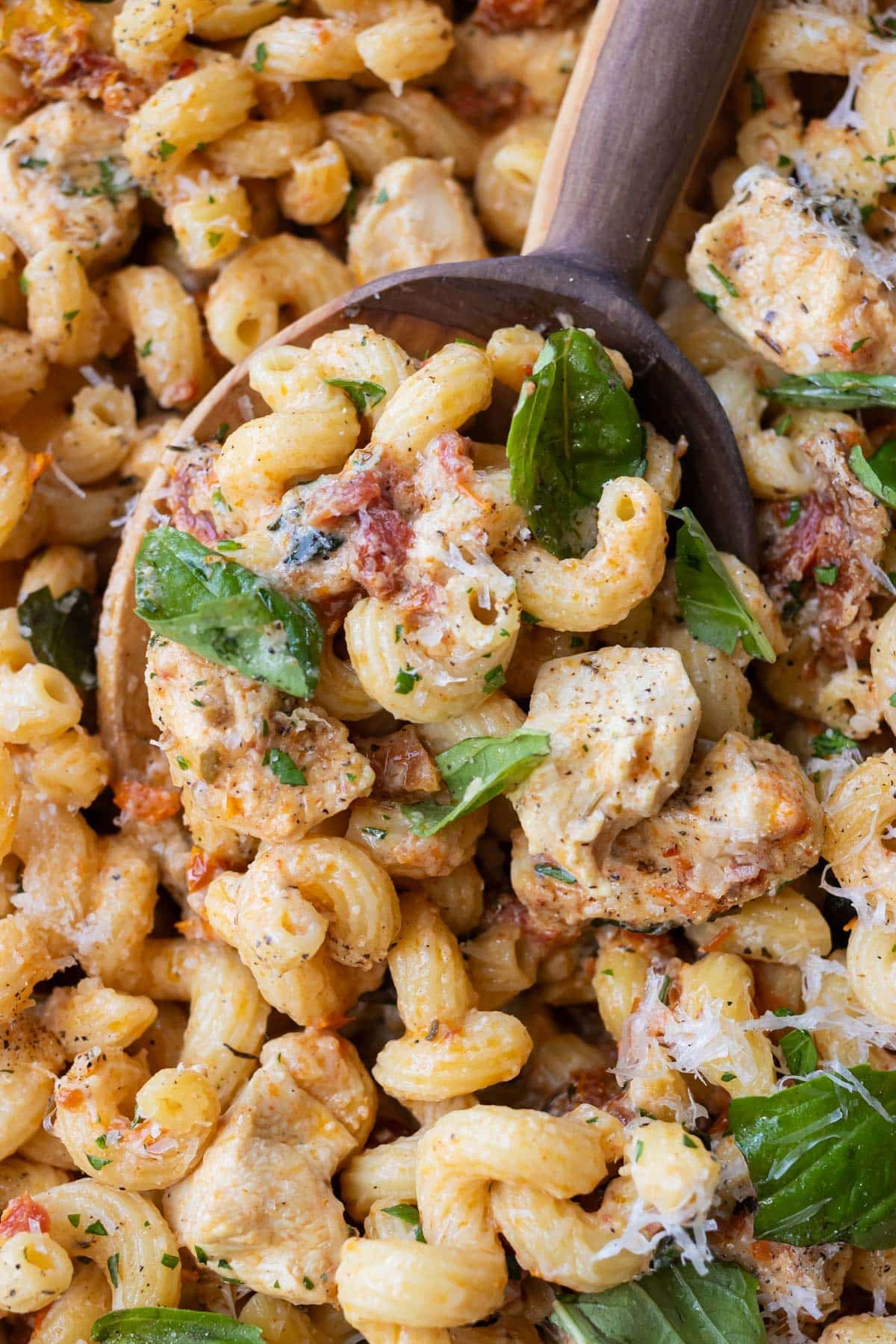 A spoon scoops up some Marry Me Chicken Pasta from a baking dish.