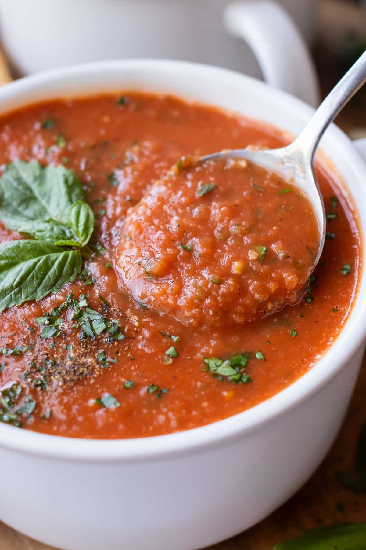Close-up of thick roasted tomato soup on a spoon showing its texture