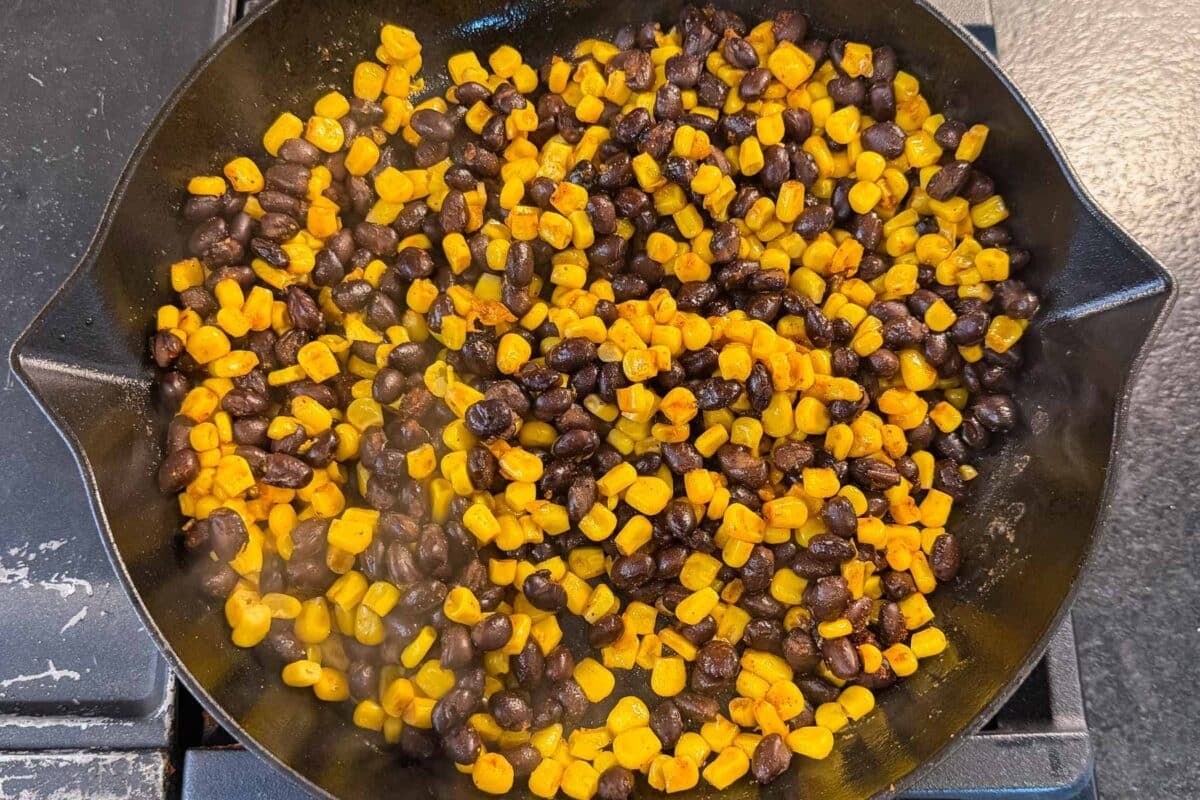 Black beans and corn warming in a skillet for sweet potato black bean bowls.