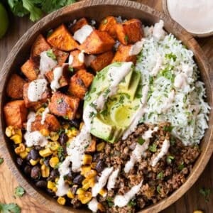 Sweet potato taco bowl with ground taco meat, crispy sweet potatoes, cilantro lime rice and chipotle crema in a bowl.