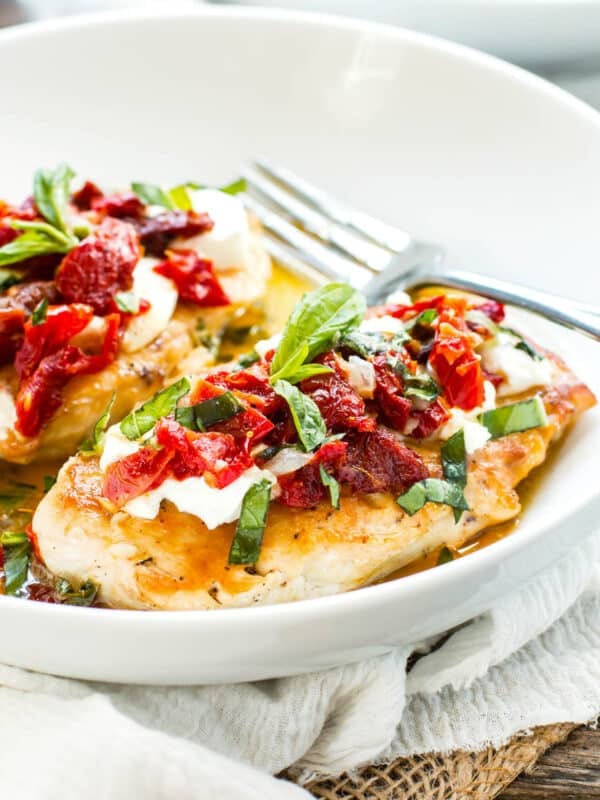 Carrabba's Chicken Bryan copycat with goat cheese and sun-dried tomatoes in a white bowl with a fork.