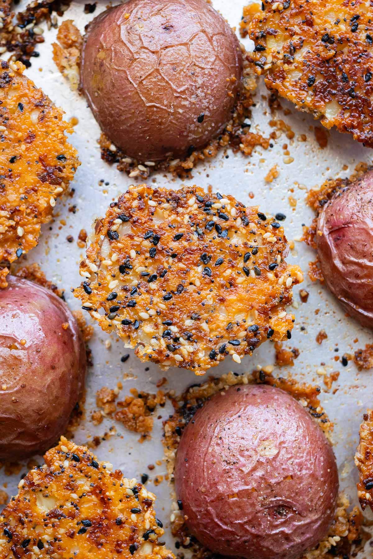 Crispy parmesan crusted potatoes with everything bagel seasoning are on a sheet pan after roasting in the oven.