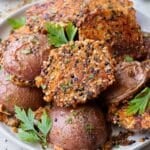 A plate of crispy everything bagel parmesan crusted potatoes are on a plate after roasting in the oven on a sheet pan.