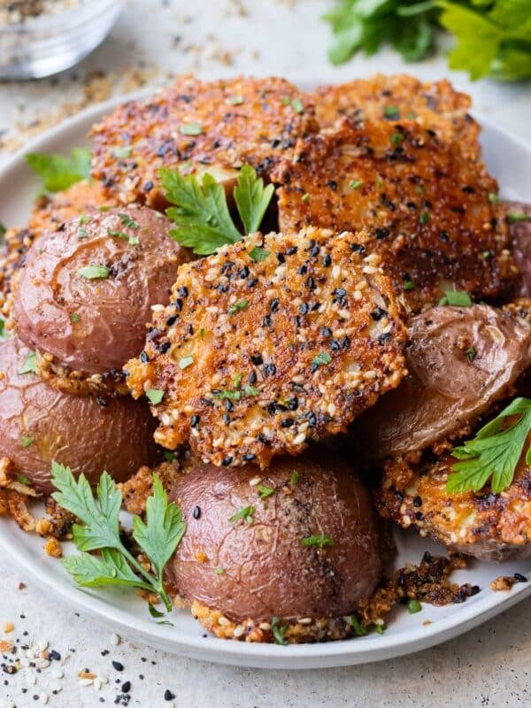 A plate of crispy everything bagel parmesan crusted potatoes are on a plate after roasting in the oven on a sheet pan.