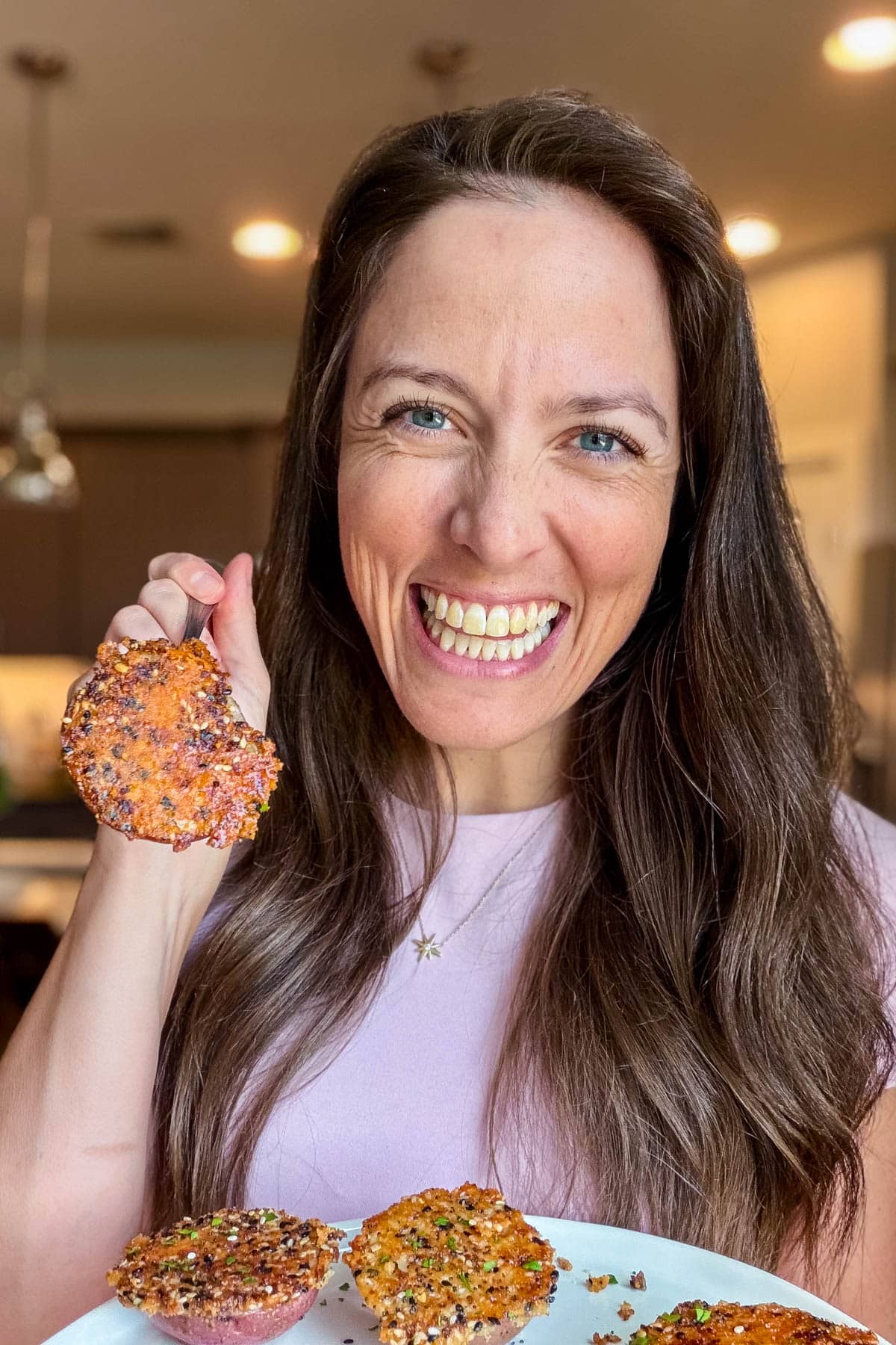 London Lea holding a crispy everything bagel parmesan crusted potato in her kitchen