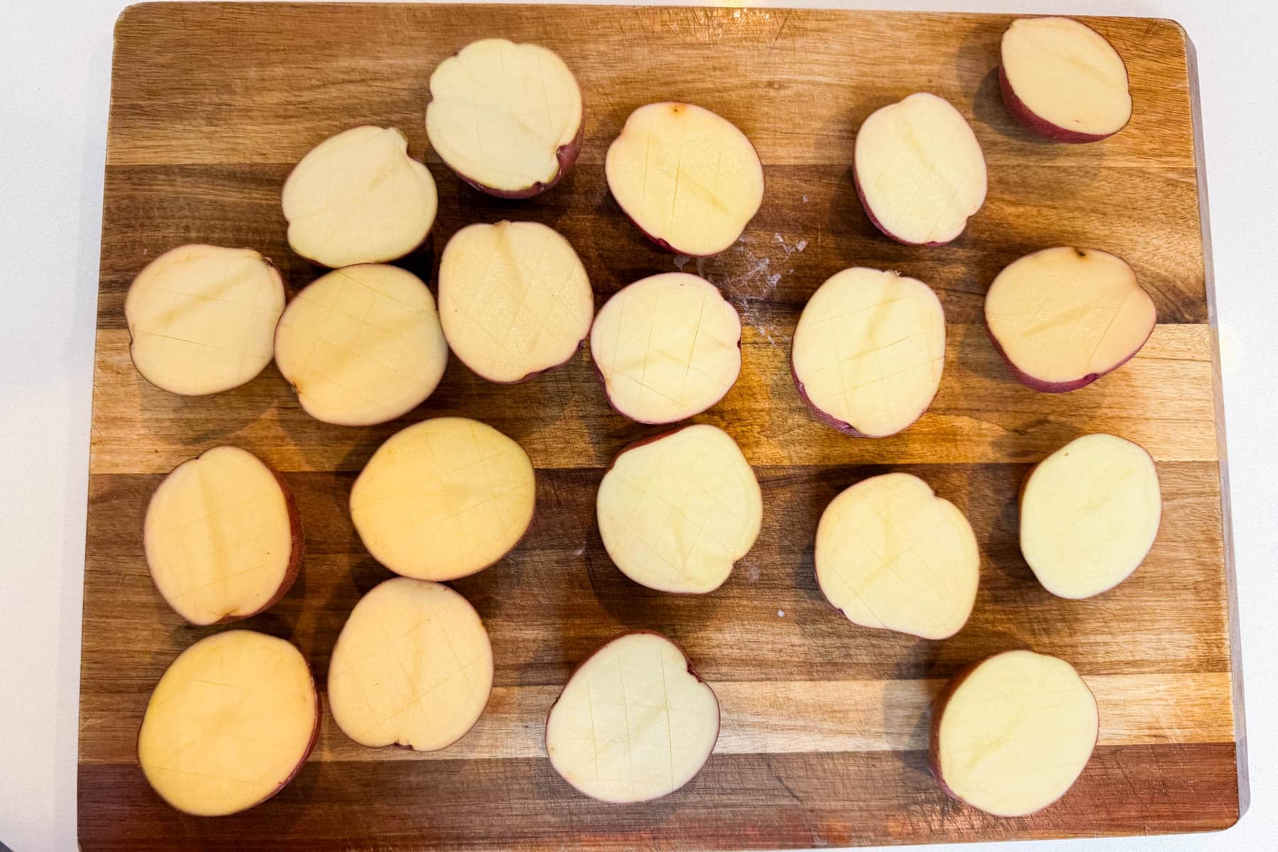 Halved red potatoes cut-side up on a wooden board for everything bagel potatoes