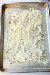 Melted butter, everything bagel seasoning, and grated Parmesan layered on a sheet pan for cheese crusted potatoes