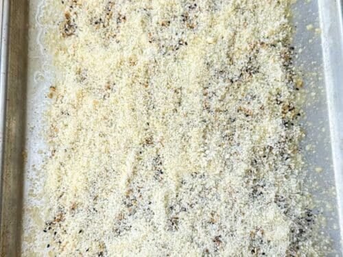 Melted butter, everything bagel seasoning, and grated Parmesan layered on a sheet pan for cheese crusted potatoes