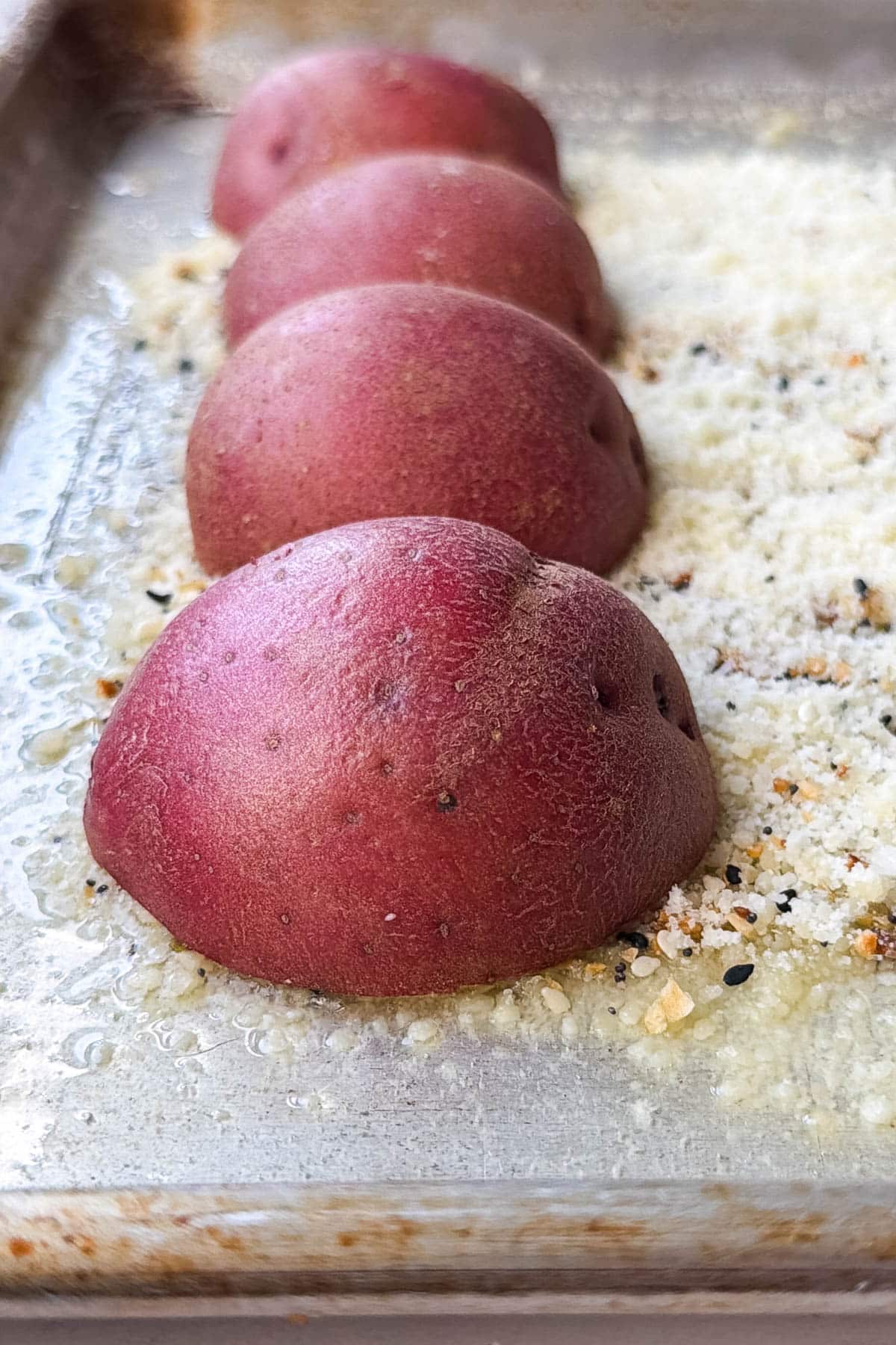 Red potato halves pressed cut-side down into Parmesan on a sheet pan