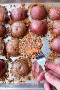Lifting a crispy parmesan potato off the pan with the everything bagel cheese crust attached