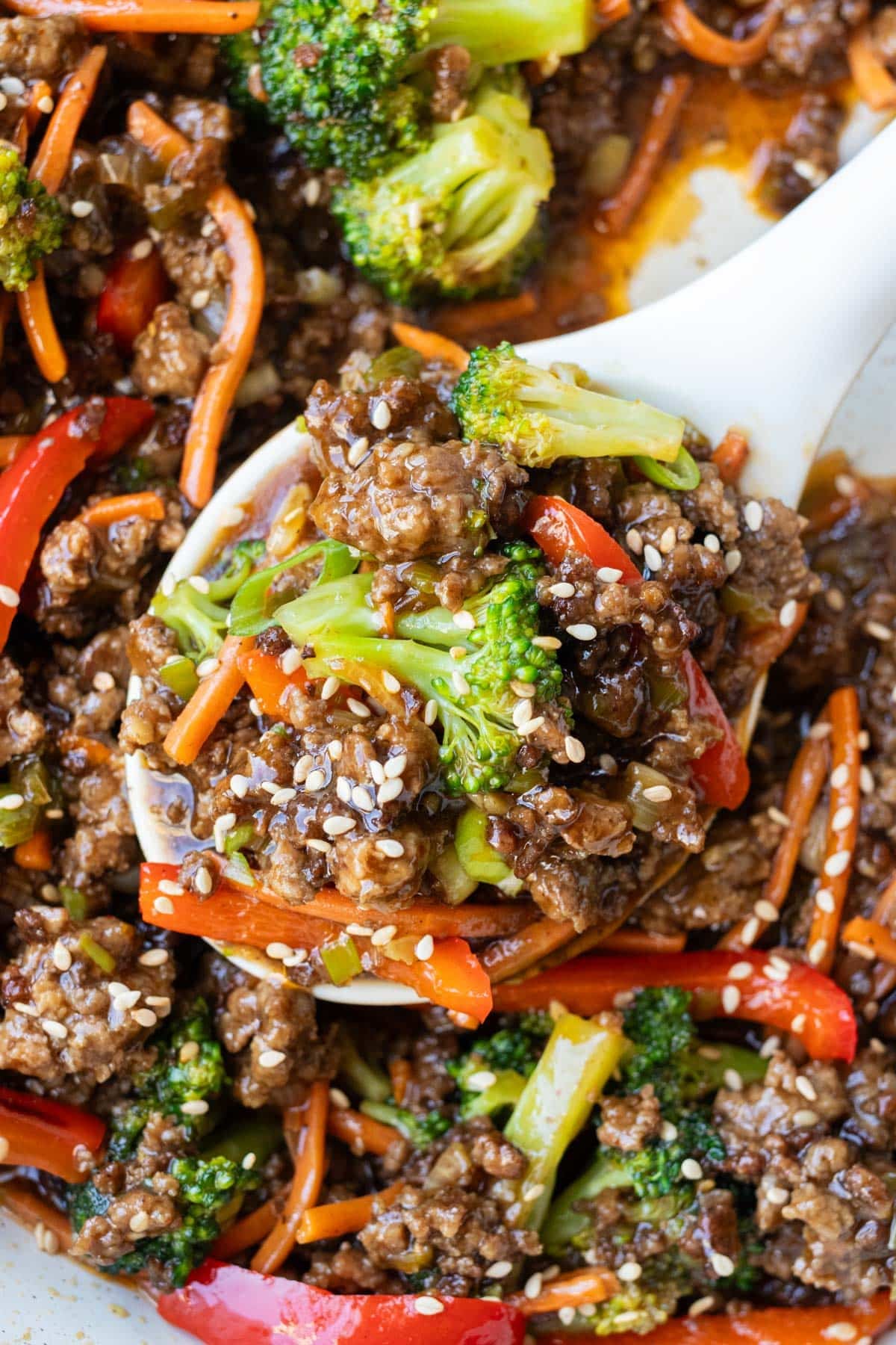 A spoonful of ground beef and broccoli stir fry with carrots and red bell pepper lifted from the skillet