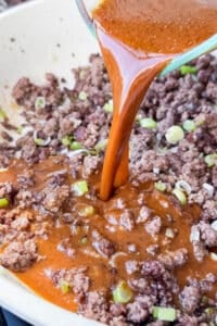 Soy-ginger stir fry sauce being poured over browned ground beef in a skillet