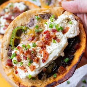 A hand holding a jalapeño popper smashed taco with whipped garlic cream cheese, bacon, and fresh jalapeños.