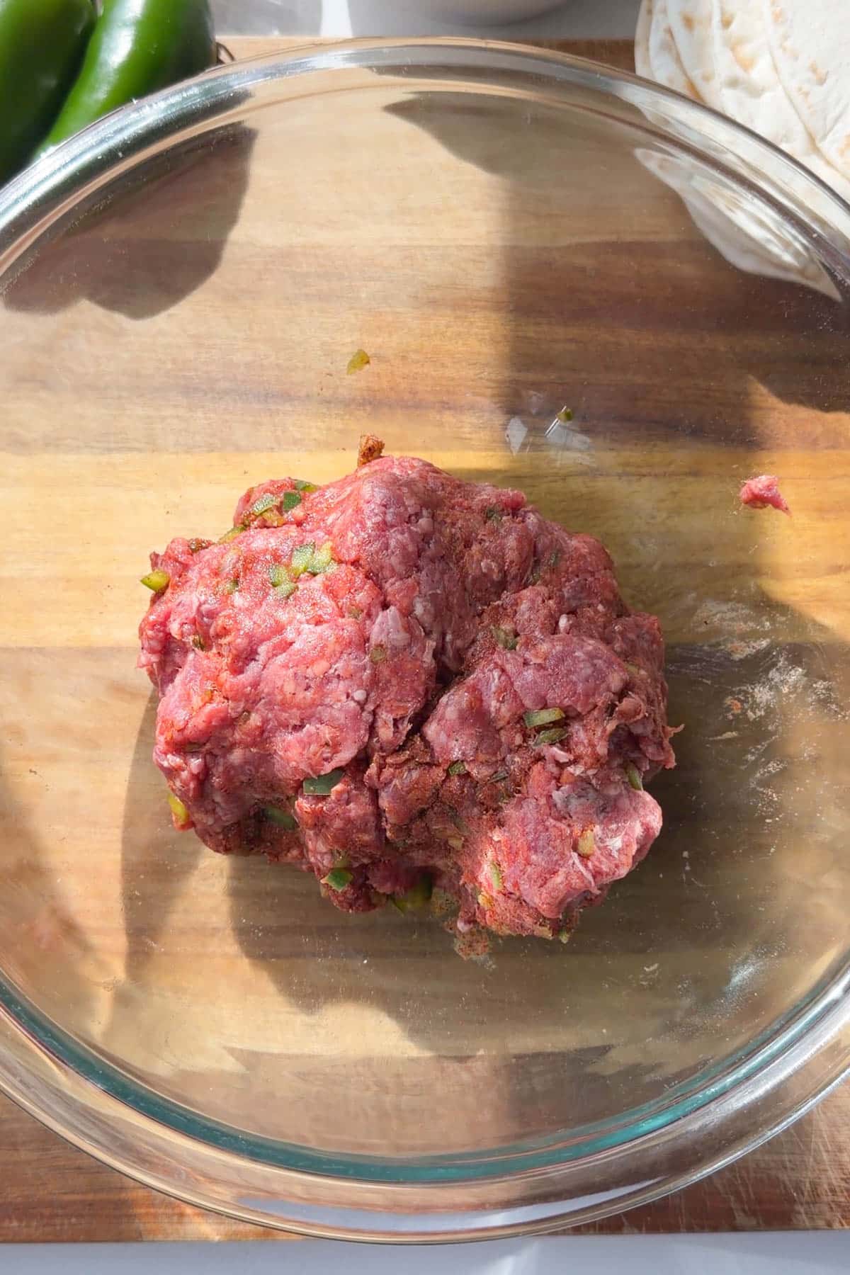 Ground beef mixed with diced jalapeño and seasonings in a glass bowl for smashed tacos