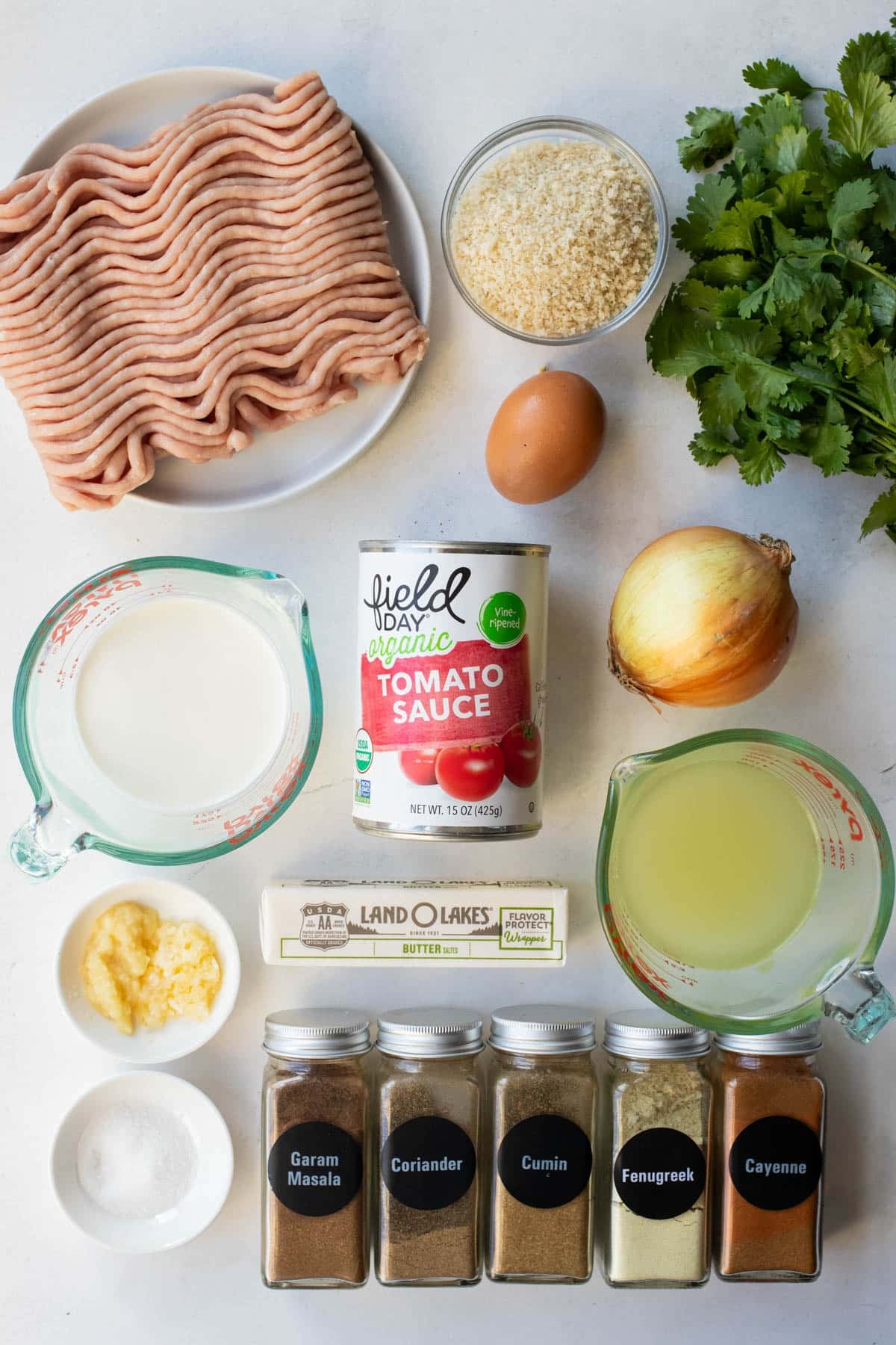 Ingredients for butter chicken meatballs, including ground chicken, panko, heavy cream, tomato sauce, fresh cilantro, and spices