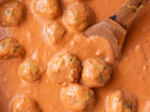 Skillet of butter chicken meatballs simmering in creamy tomato sauce