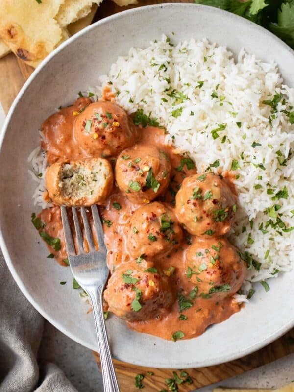 Butter chicken meatballs served over basmati rice with naan and fresh cilantro.