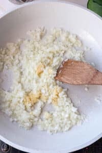 Diced onion, garlic, and ginger softening in butter in a skillet for butter chicken sauce