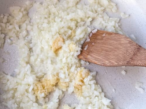 Diced onion, garlic, and ginger softening in butter in a skillet for butter chicken sauce