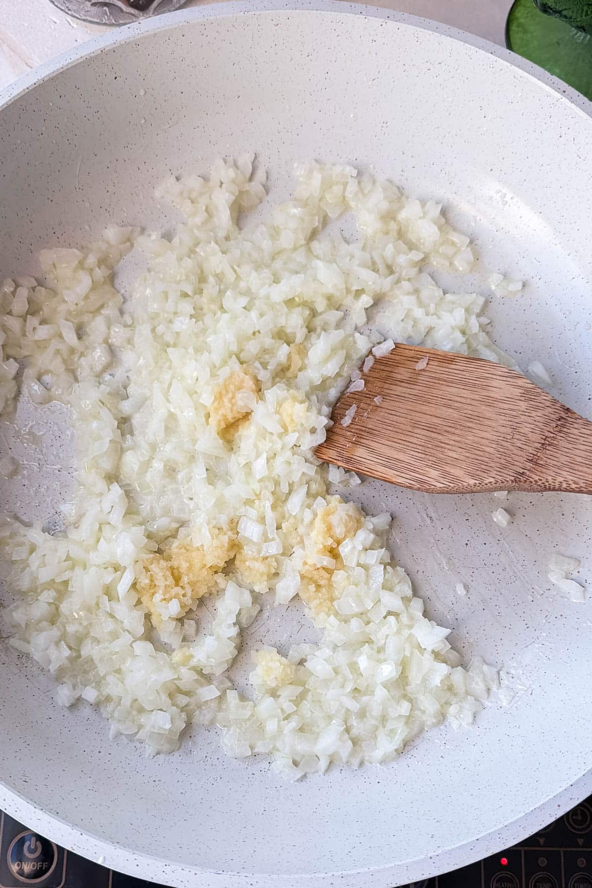 Diced onion, garlic, and ginger softening in butter in a skillet for butter chicken sauce