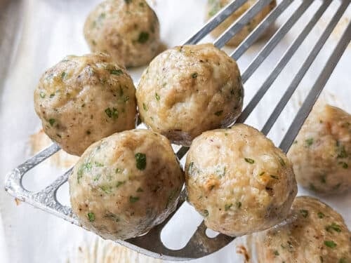 Golden baked chicken meatballs on a spatula, ready for the butter chicken sauce
